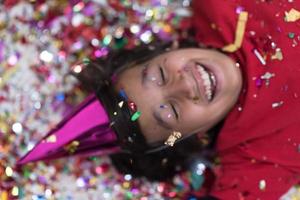 kid blowing confetti while lying on the floor photo