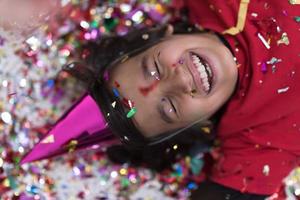 kid blowing confetti while lying on the floor photo