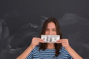 mujer sosteniendo un billete frente a un tablero de dibujo de tiza foto