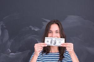 mujer sosteniendo un billete frente a un tablero de dibujo de tiza foto