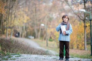 lindo niño en el parque comiendo palomitas de maíz foto