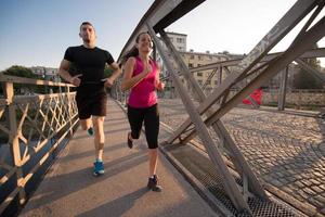 pareja joven corriendo por el puente en la ciudad foto
