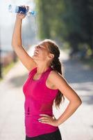 woman pouring water from bottle on her head photo