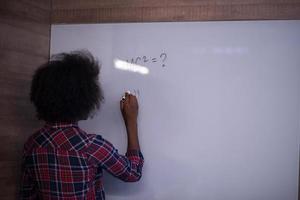 African American woman writing on a chalkboard in a modern office photo