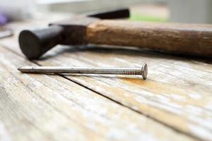 martillo y clavos sobre fondo de madera, madera y cabeza de óxido martillo de hierro sobre tabla de madera con taller al aire libre. foto