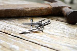 martillo y clavos sobre fondo de madera, madera y cabeza de óxido martillo de hierro sobre tabla de madera con taller al aire libre. foto