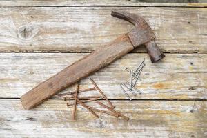 Hammer and nails on wooden background, wood and rust head iron hammer lying on wooden board with outdoor workshop. photo