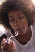 a young African American woman eating pasta photo