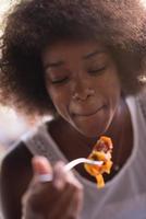 una joven afroamericana comiendo pasta foto