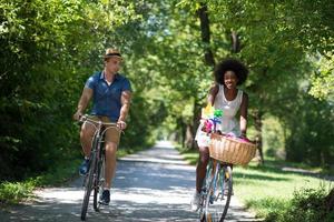 joven pareja multiétnica dando un paseo en bicicleta en la naturaleza foto