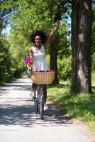 pretty young african american woman riding a bike in forest photo