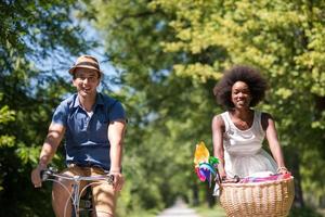 joven pareja multiétnica dando un paseo en bicicleta en la naturaleza foto