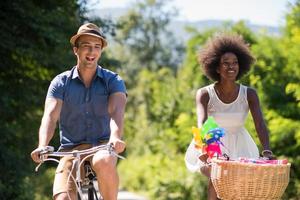 joven pareja multiétnica dando un paseo en bicicleta en la naturaleza foto