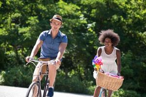 joven pareja multiétnica dando un paseo en bicicleta en la naturaleza foto