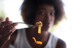 una joven afroamericana comiendo pasta foto