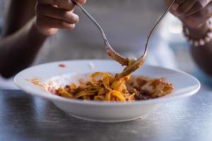 una joven afroamericana comiendo pasta foto