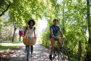 joven pareja multiétnica dando un paseo en bicicleta en la naturaleza foto