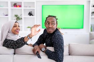 African Couple Sitting On Sofa Watching TV Together photo