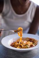 a young African American woman eating pasta photo