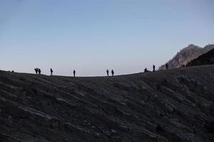 senderismo turistas disfrutando de la vista del amanecer en java indonesia del monte ijen foto