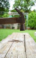 martillo y clavos sobre fondo de madera, madera y cabeza de óxido martillo de hierro sobre tabla de madera con taller al aire libre. foto