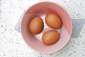 Three fresh eggs in a bowl are cooking. photo