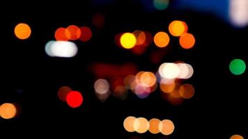 verschwommenes bokeh von autos im verkehr auf der straße bei nacht. abstraktes helles unscharfes farbiges bokeh. video