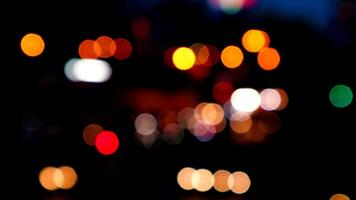 verschwommenes bokeh von autos im verkehr auf der straße bei nacht. abstraktes helles unscharfes farbiges bokeh. video