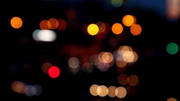 verschwommenes bokeh von autos im verkehr auf der straße bei nacht. abstraktes helles unscharfes farbiges bokeh. video