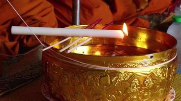 de kaars werd op de wijwaterschaal geplaatst en brandde. dat is een religieuze ceremonie van thailand. video