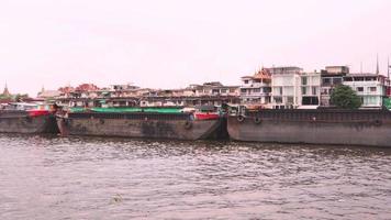 Frachtschiff, das von Booten auf dem Fluss Chao Phraya, Thailand, geschleppt wird