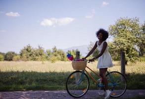 pretty young african american woman riding a bike in forest photo