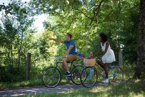 joven pareja multiétnica dando un paseo en bicicleta en la naturaleza foto