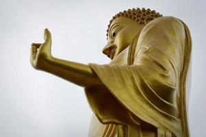 A large, golden-yellow Buddha image is located on the Mekong River. photo