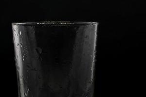 gotas de agua sobre un vaso de fondo negro. foto