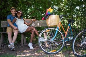 joven pareja multiétnica dando un paseo en bicicleta en la naturaleza foto