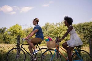 joven pareja multiétnica dando un paseo en bicicleta en la naturaleza foto