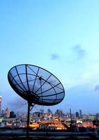 antena parabólica de comunicación de antena negra sobre el cielo del atardecer en el paisaje urbano foto