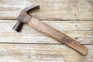 Hammer and nails on wooden background, wood and rust head iron hammer lying on wooden board with outdoor workshop. photo