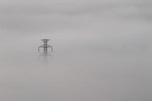 líneas eléctricas y pilones que emergen de la niebla