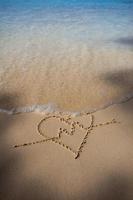 corazones dibujados en la arena de una playa foto