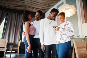 Happy african friends standing and chatting in cafe. Group of black peoples meeting in restaurant. photo