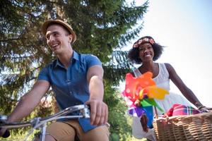 joven pareja multiétnica dando un paseo en bicicleta en la naturaleza foto