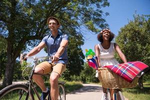 joven pareja multiétnica dando un paseo en bicicleta en la naturaleza foto