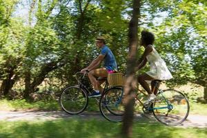 joven pareja multiétnica dando un paseo en bicicleta en la naturaleza foto