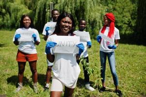 un grupo de felices voluntarios africanos sostiene un tablero en blanco con un cartel de unidad en el parque. Concepto de voluntariado, caridad, personas y ecología de África. foto