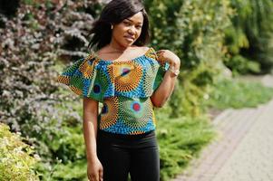 African american girl in coloured shirt and black pants posed outdoor. Fashionable black woman. photo