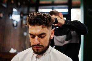 apuesto hombre barbudo en la barbería, peluquero en el trabajo. foto