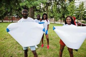 Group of happy african volunteers hold empty blank board in park. Africa volunteering, charity, people and ecology concept. Free space for your text. photo