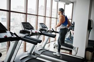 Fit and muscular arabian man running on treadmill in gym. photo